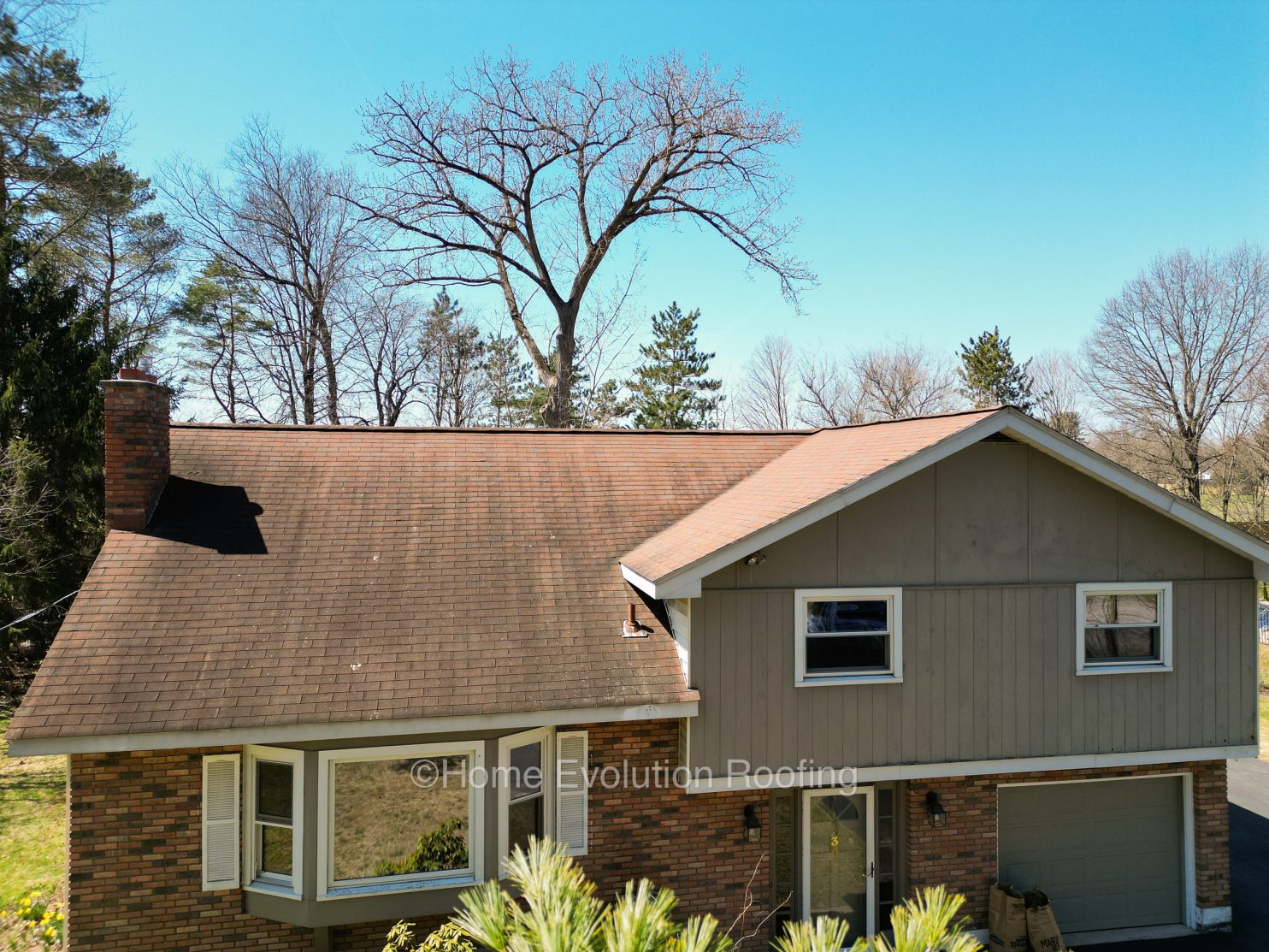 Home Evolution Roofing expert inspecting a wavy roof in Albany, NY, assessing structural and material issues.