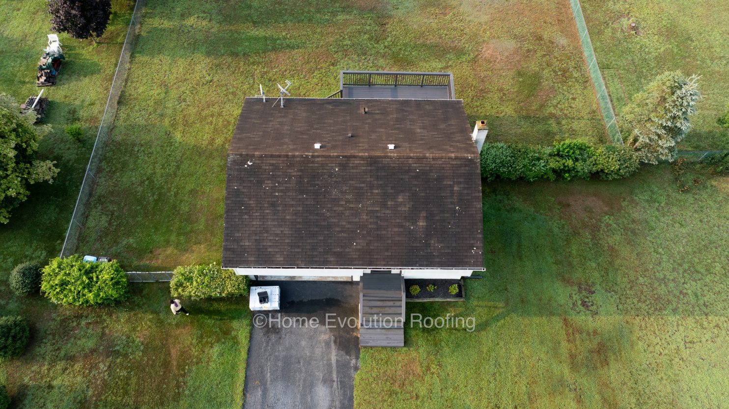 Professional Utica roofers safely removing black streaks and moss from an asphalt shingle roof to restore its appearance and longevity