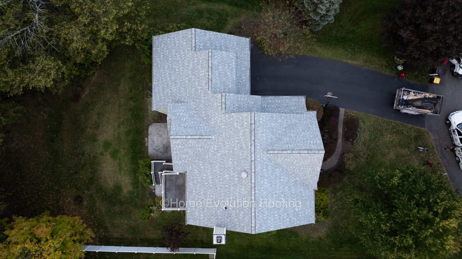 Storm-damaged roof in Utica, NY with missing shingles and visible water damage.