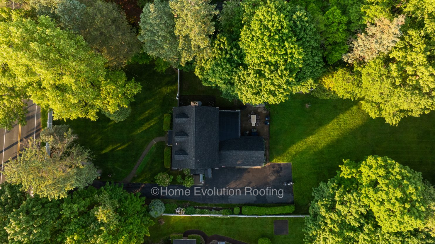 A professional roofer inspecting a home roof in Amsterdam NY for signs of damage.