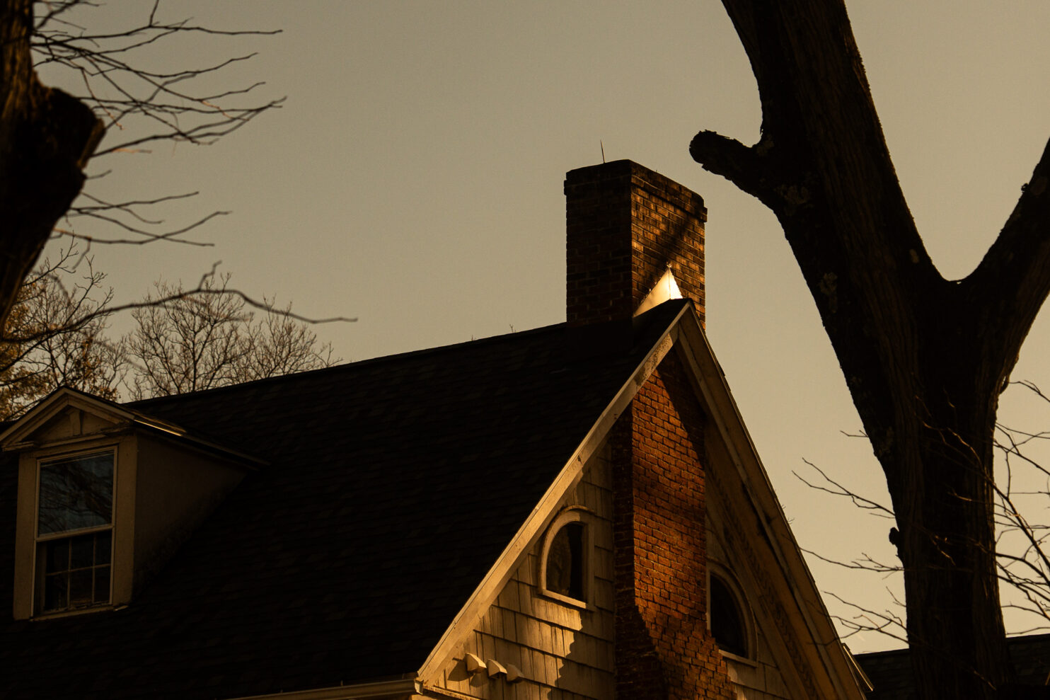 Chimney repair specialist inspecting brick chimney on Albany home during fall